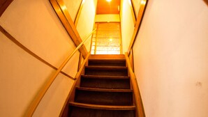 Una escalera de madera con barandilla que lleva a una puerta con panel de vidrio.