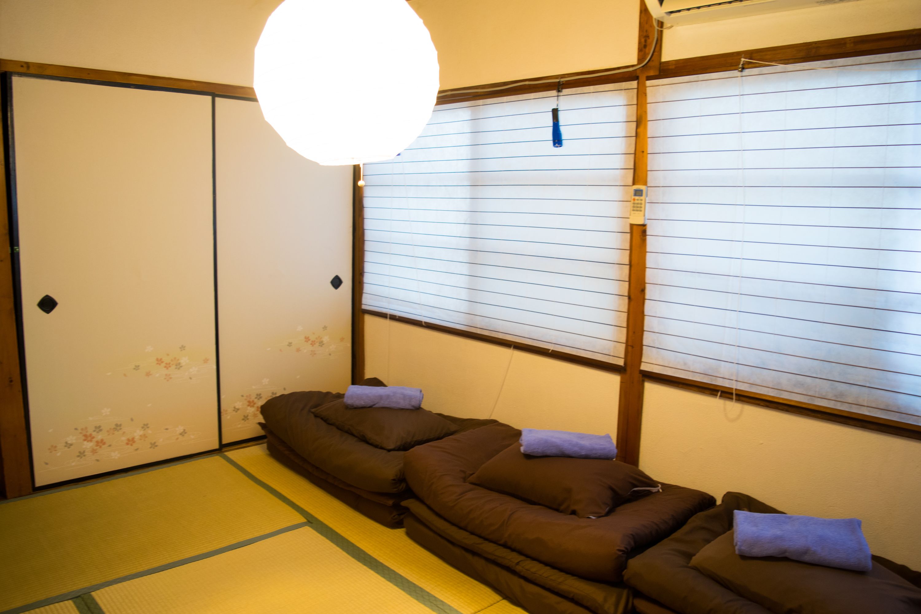 Une pièce de style japonais traditionnel, avec un sol recouvert de tatamis, un lit bas en bois et des paravents en papier de riz (shoji).