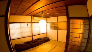 Una habitación japonesa tradicional con suelo de tatami, futón, puertas correderas y pantalla shoji.