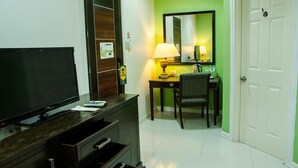 A hotel room with a TV, a desk with a lamp, a chair, and a door. - Dreamwave Hotel Santiago City (Santiago City)