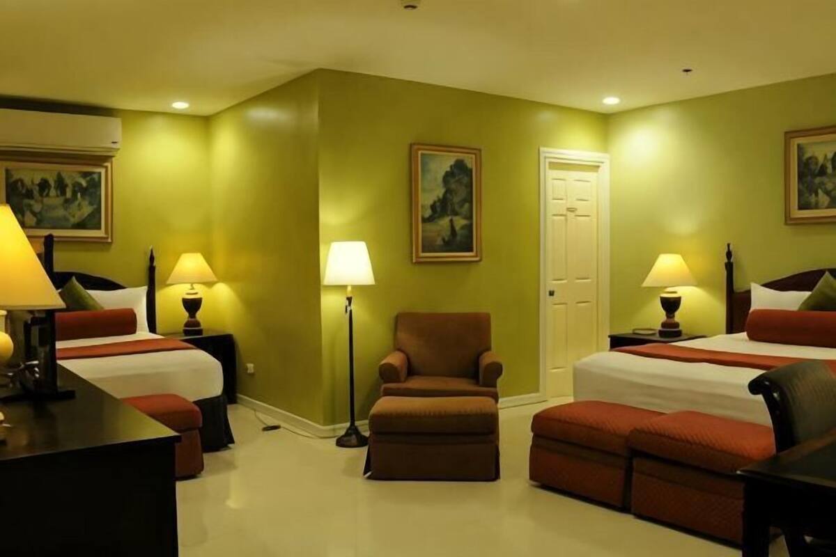 Une chambre d’hôtel avec deux lits, un bureau, une chaise et deux lampes.
