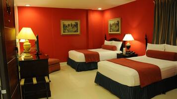 A hotel room with two beds, red walls, and two lamps.