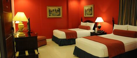 Habitación de hotel con dos camas, paredes rojas y dos lámparas.