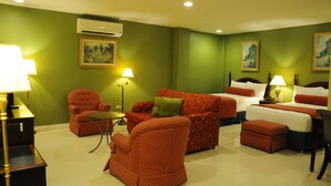 A hotel room with green walls, a sofa, a chair, a bed, and a small table. - Dreamwave Hotel Santiago City (Santiago City)