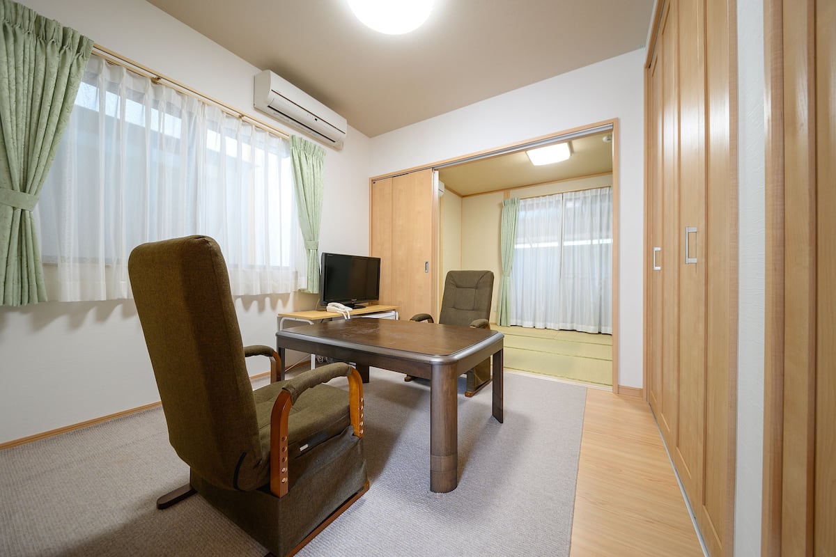 Ein Zimmer mit einem Holzschrank, einem Fernseher, einem braunen Sessel und einem Tisch.