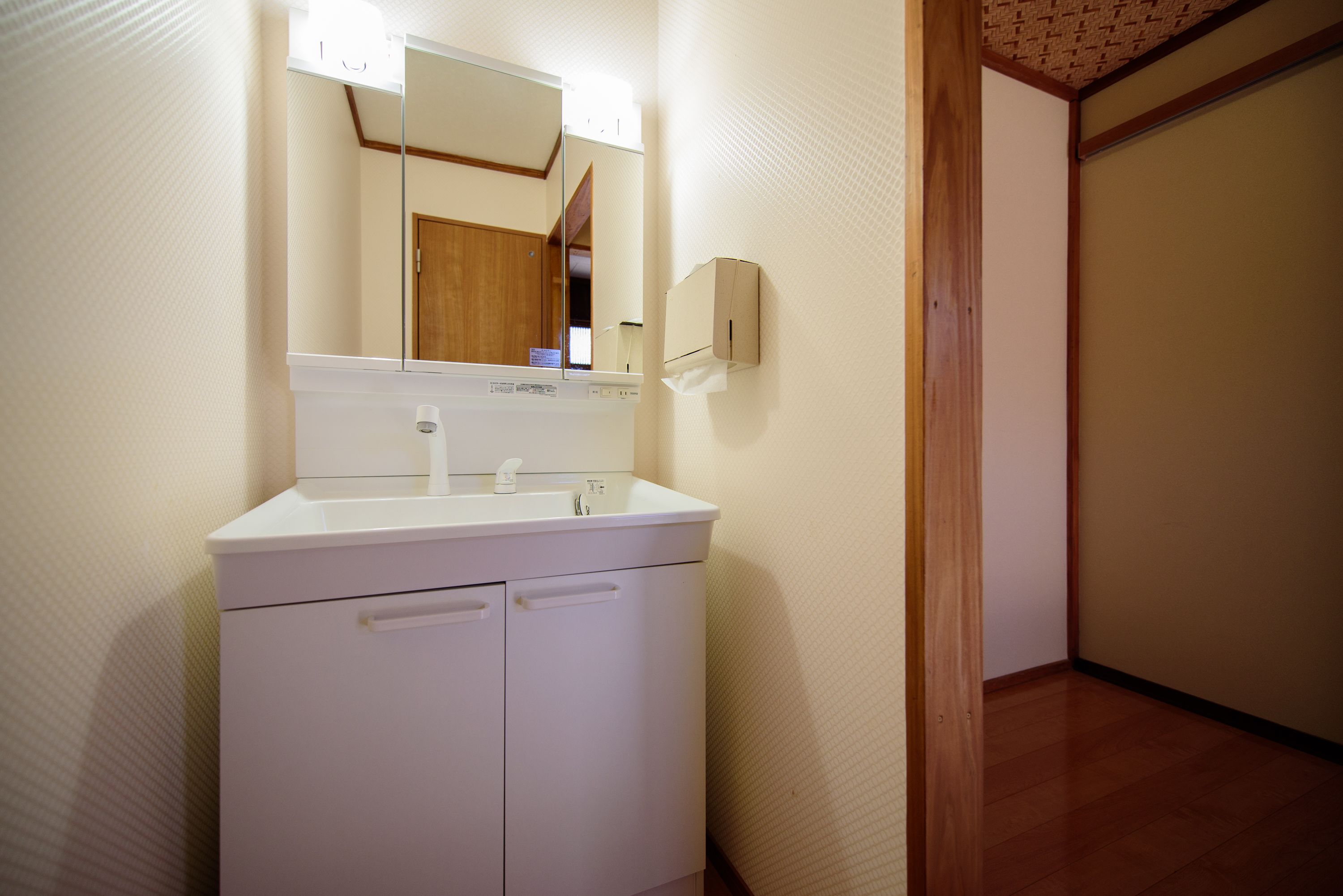 A bathroom with a white sink, mirror, and cabinet.