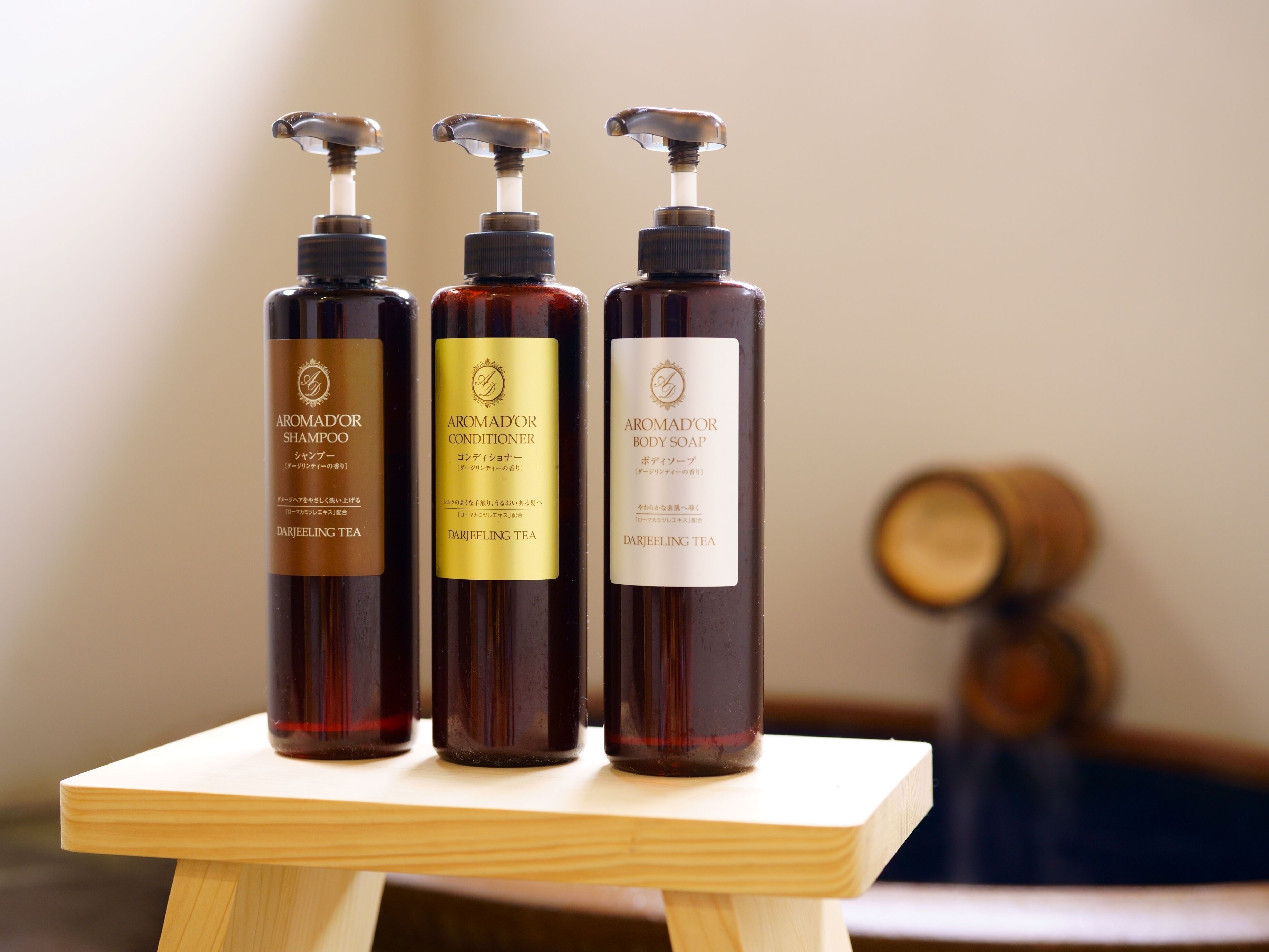 Tres botellas de productos a base de té Darjeeling sobre un taburete de madera.