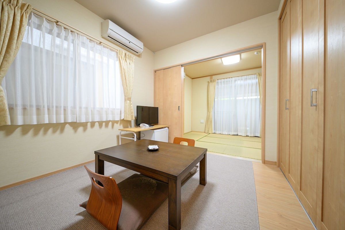 Ein Zimmer mit Holztisch, Fernseher und Kleiderschrank.