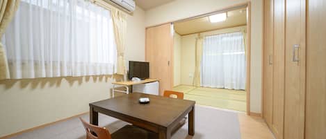 Una habitación con una mesa de madera, un televisor y un armario.