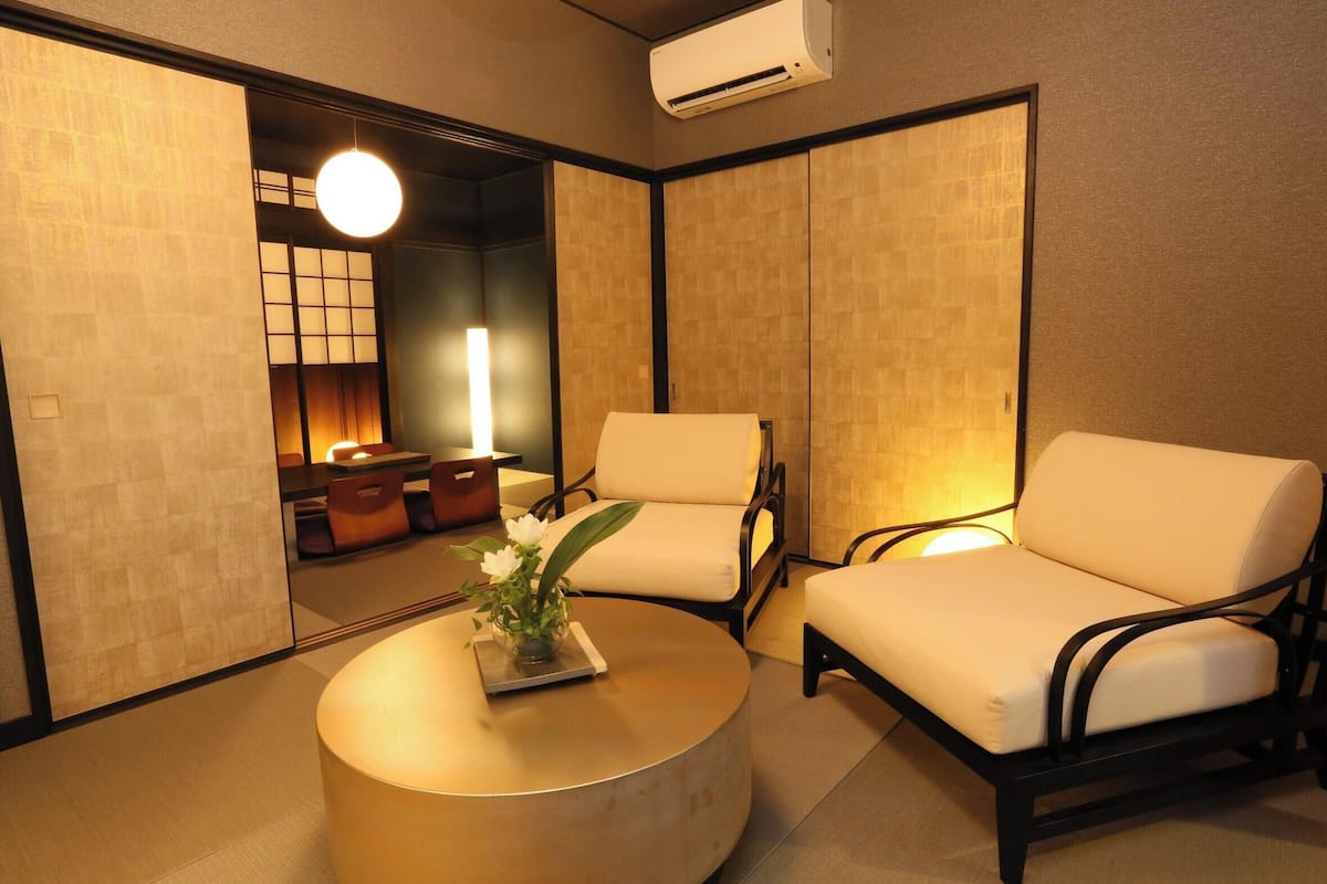 A room with a round table, two chairs, a small table with a vase, and a traditional Japanese sliding door.