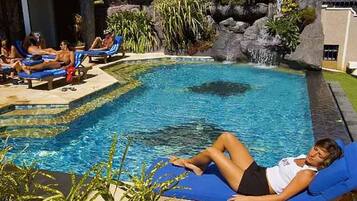 A pool area with lounge chairs and a waterfall feature.
