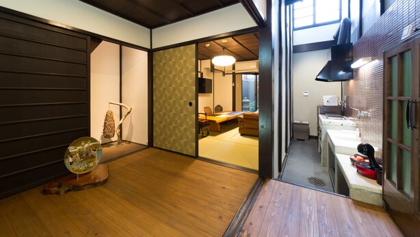 Un intérieur moderne avec un plancher en bois, un coin repas comprenant une table et des chaises, et un espace cuisine avec un évier et un plan de travail.