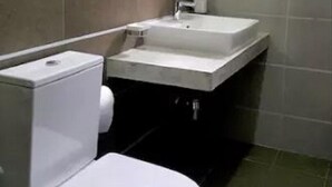 Een moderne badkamer met toilet, wastafel en spiegel.