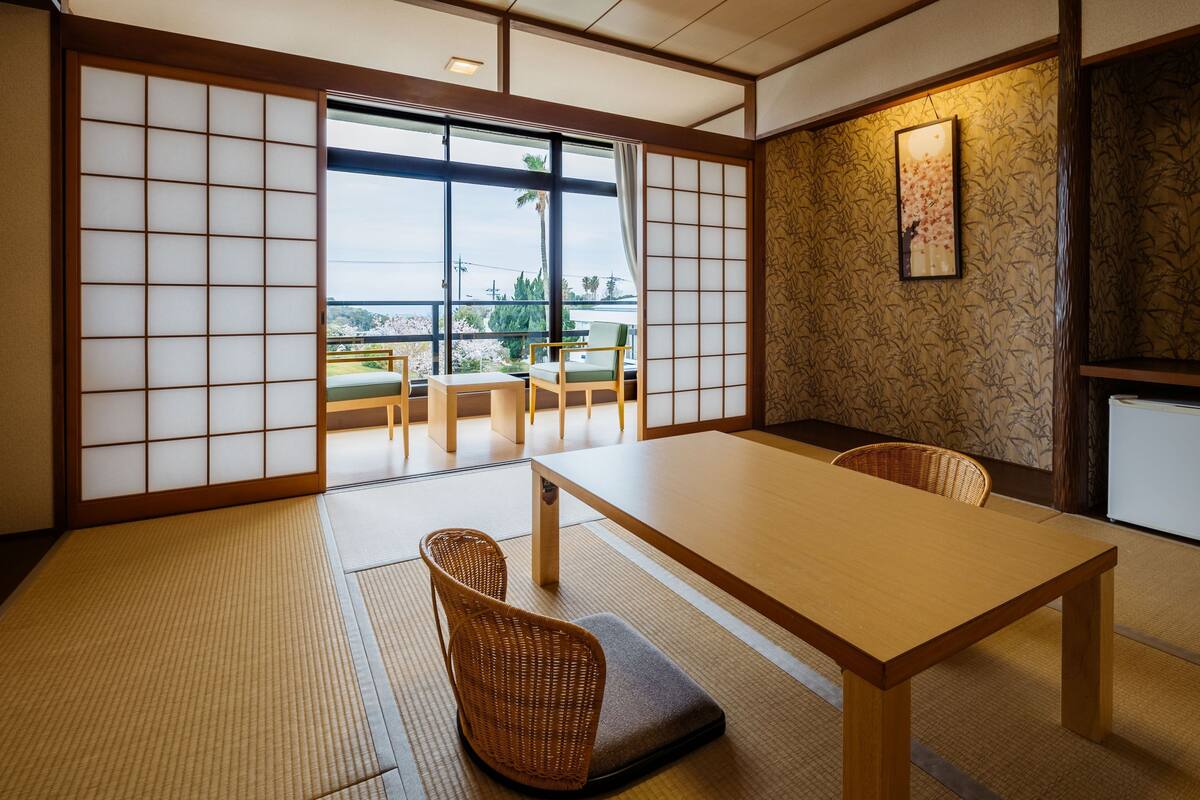 A traditional Japanese room with tatami flooring, a low table, and a view of the outdoors.