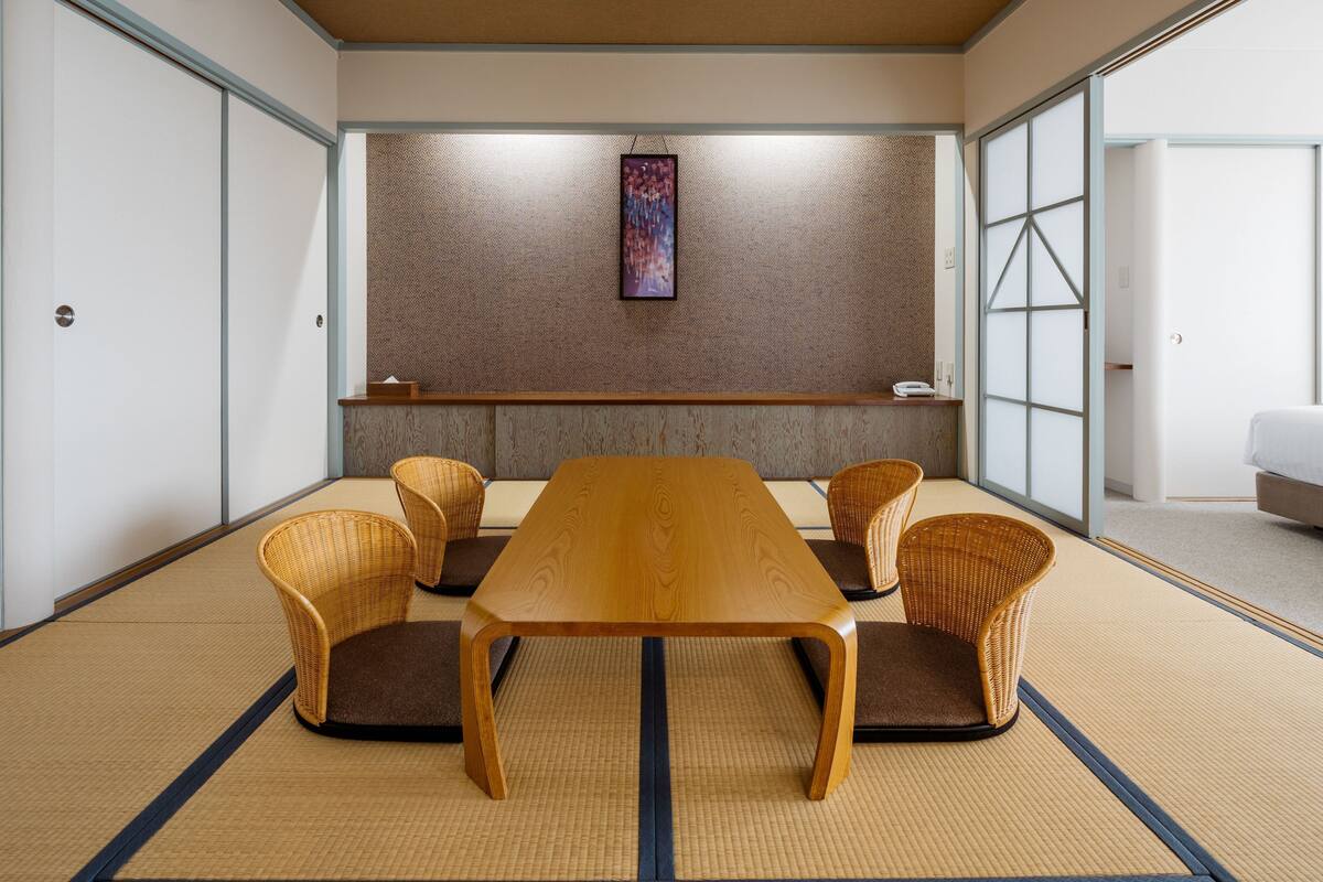 A traditional Japanese-style room with tatami flooring, a low wooden table, and woven chairs.