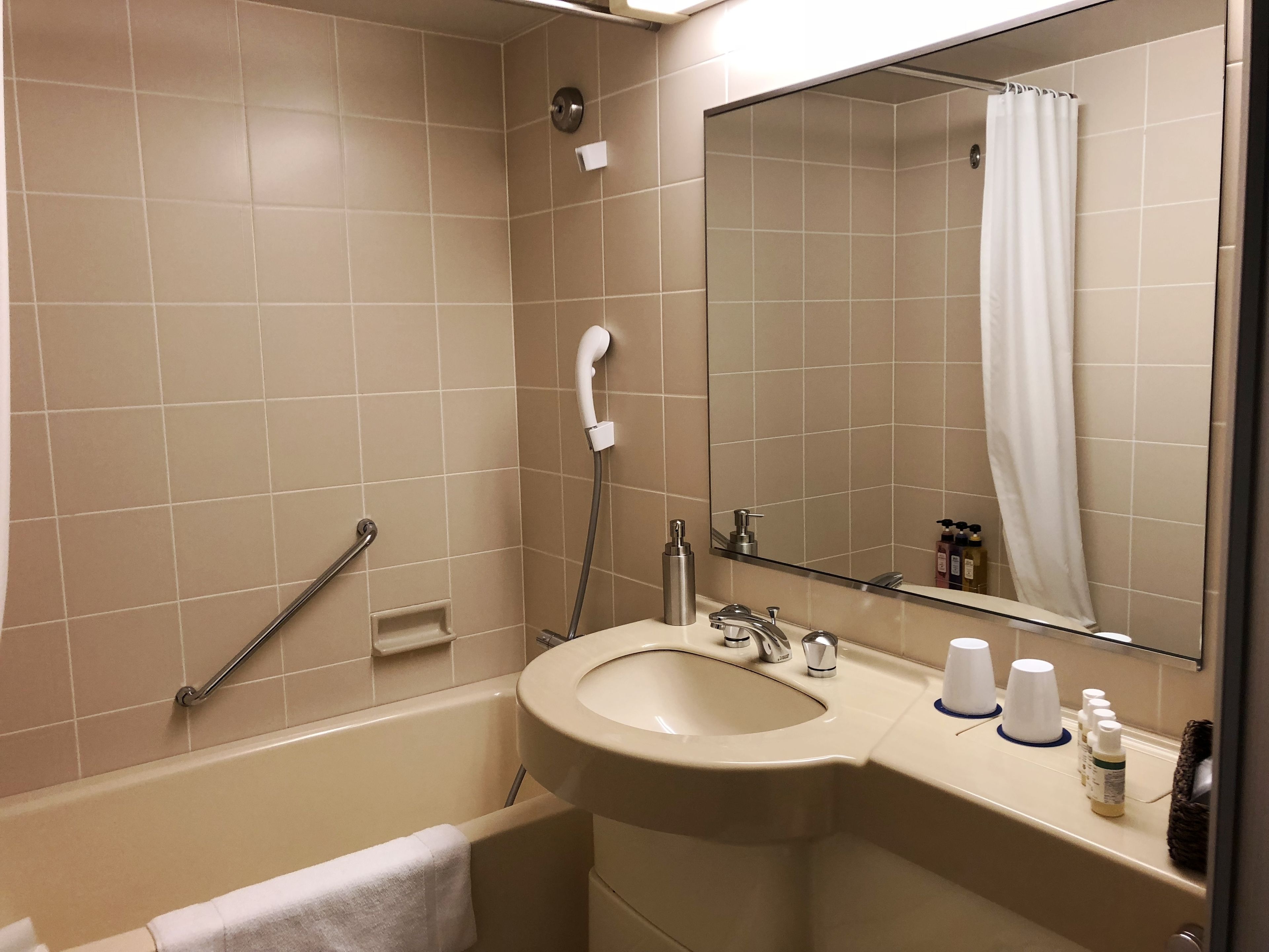 A bathroom with a bathtub, a sink with a mirror, and a shower curtain.