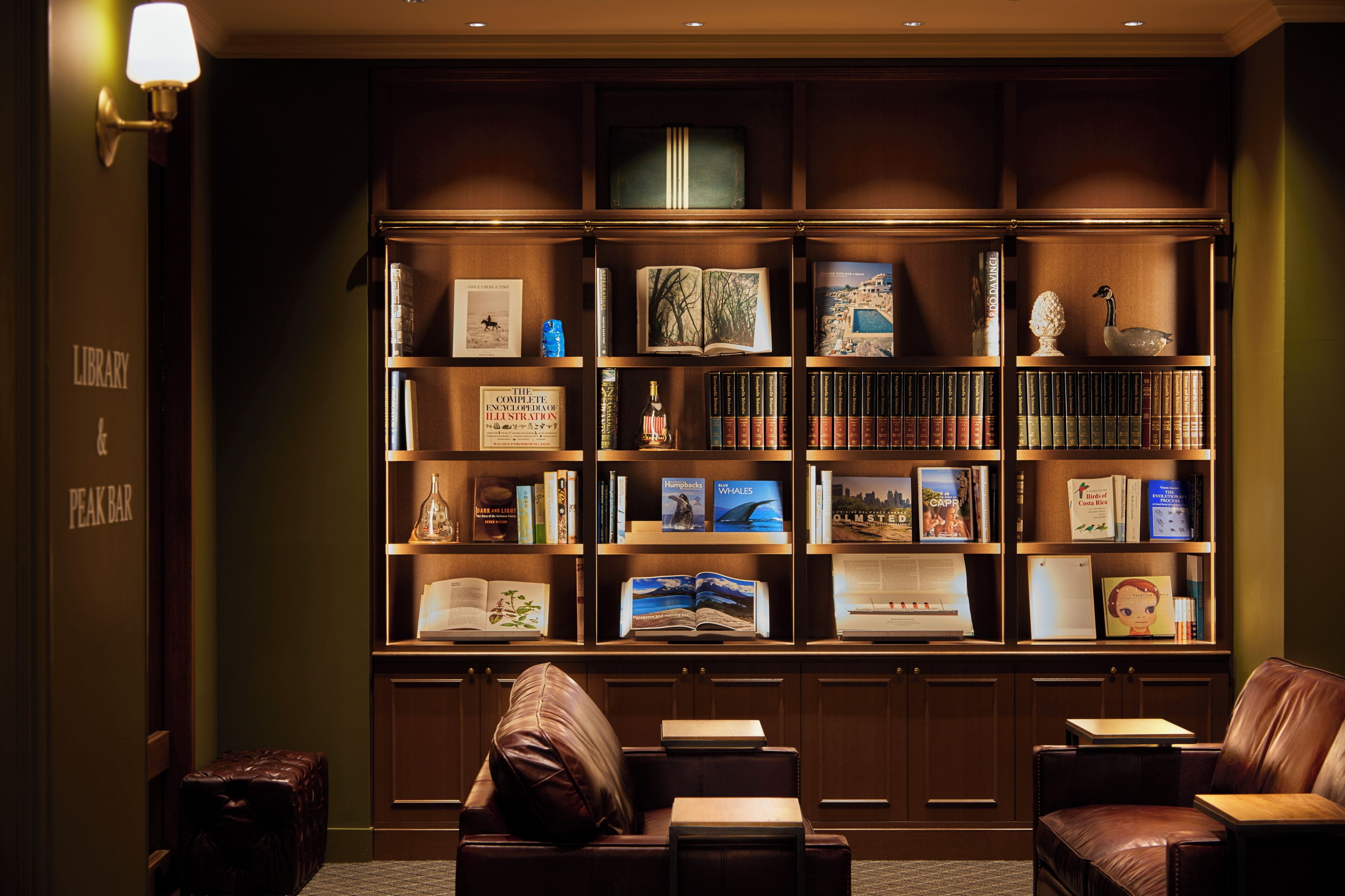 Una biblioteca con estanterías, asientos de cuero y una lámpara.