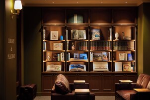 Una biblioteca con estanterías, asientos de cuero y una lámpara.