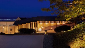 A modern building with a glass facade, a covered outdoor area, and a view of the landscape.