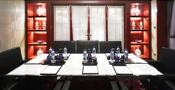 Un salón de conferencias con una larga mesa, varias sillas y botellas de agua en cada asiento.