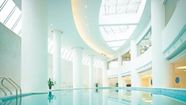 Una piscina interior amplia con techos altos y ventanas grandes.