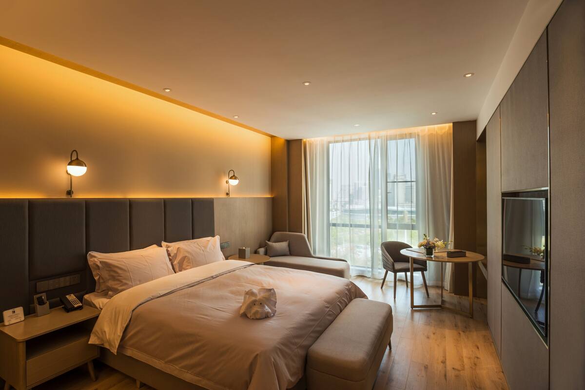Una habitación de hotel moderna con una cama grande, mesitas de noche, un escritorio y un televisor.