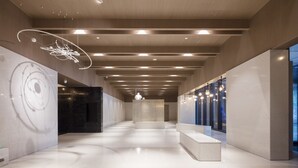En modern inredning med en lång korridor, infälld belysning och en central sittgrupp.