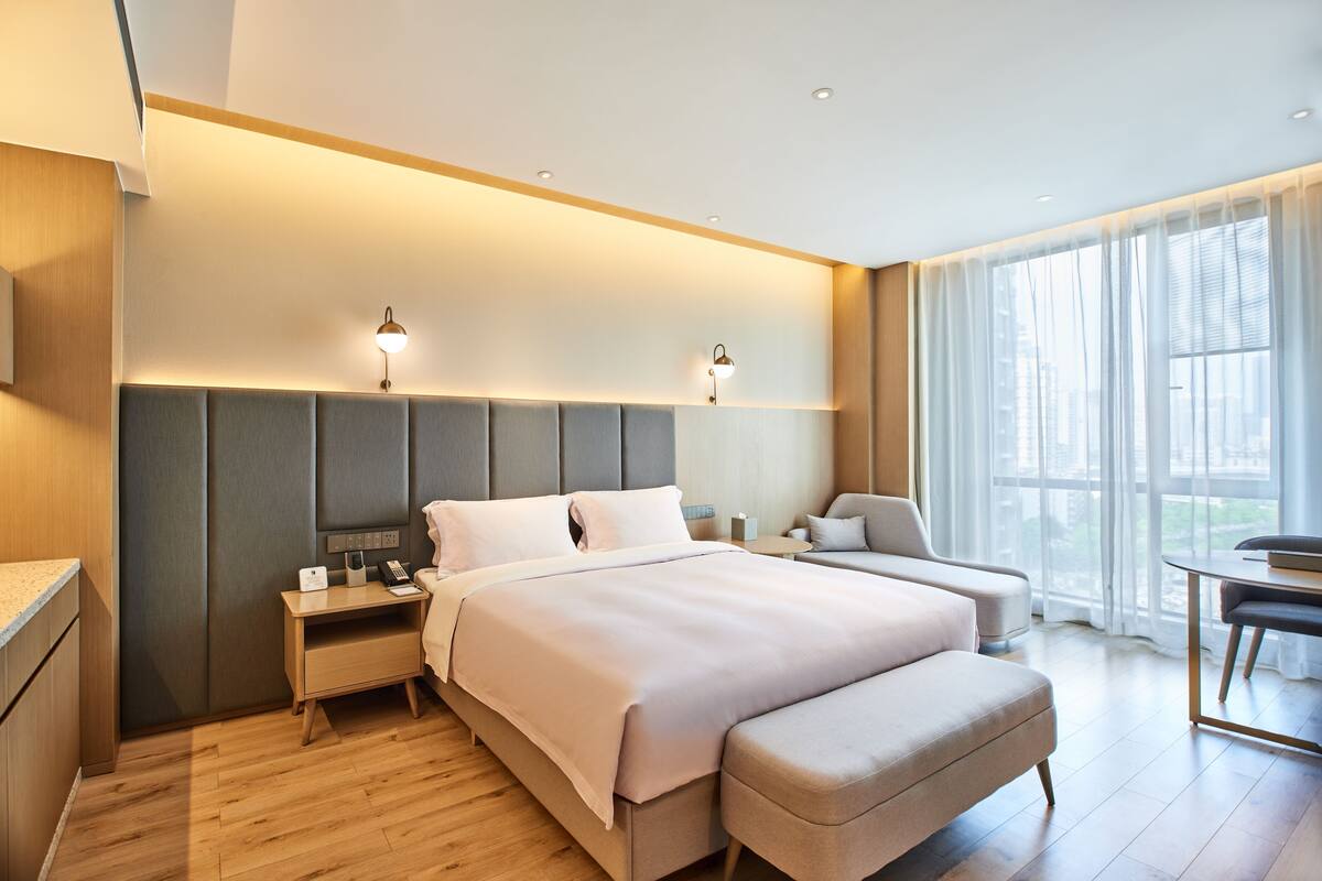 Una habitación de hotel moderna con una cama grande, mesitas de noche, un escritorio y una silla.