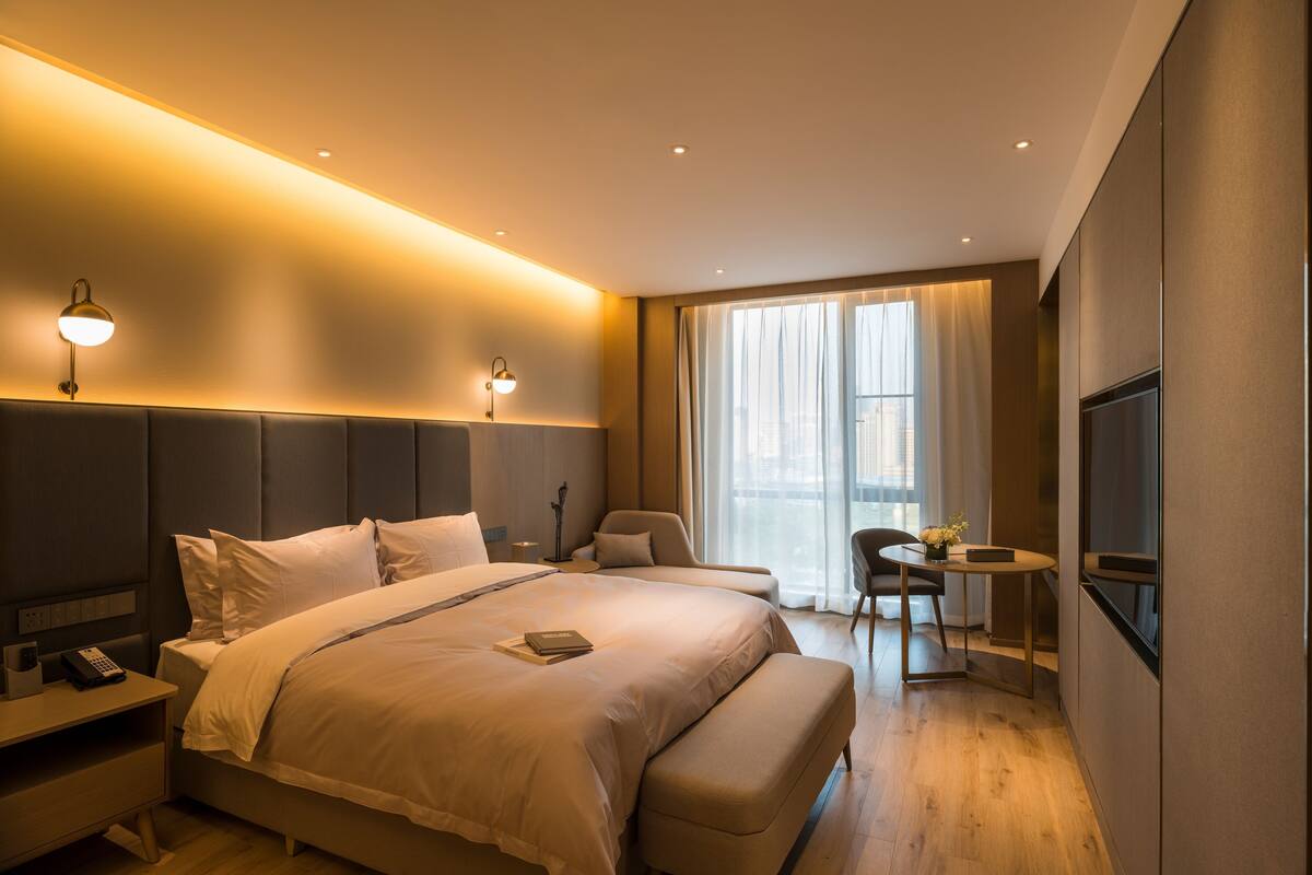 Una habitación de hotel moderna con una cama grande, mesitas de noche, un escritorio y un televisor.