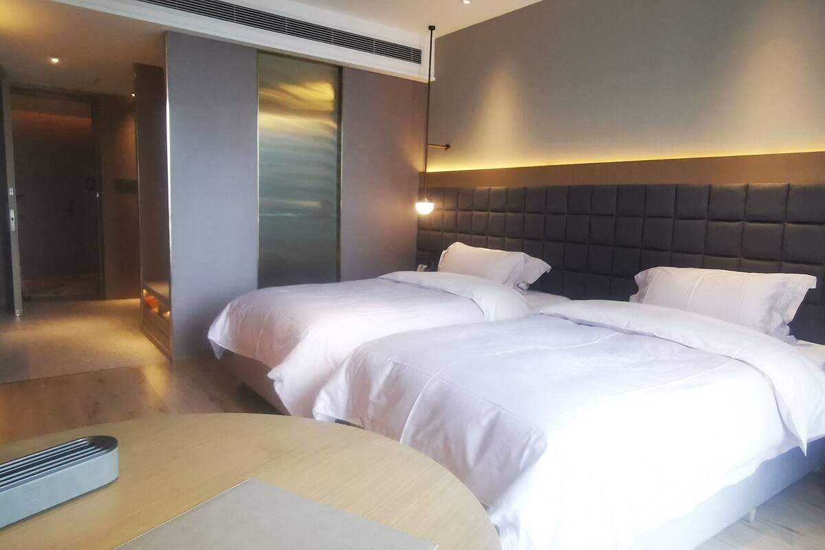 Una habitación de hotel moderna con dos camas, una mesita de noche, un escritorio y una silla.