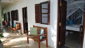 Corredor com bancos de madeira e portas, levando a um quarto com cama e dossel.