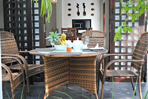 A wicker dining table with chairs, a fruit bowl, and a coffee pot. - Wasantha Garden Hotel (Weligama)