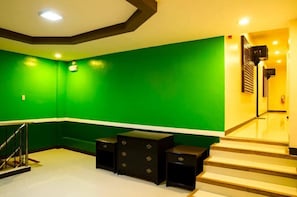 A room with green walls, a staircase, and black nightstands.