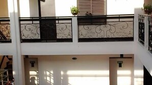 Un edificio de varios niveles con piso de baldosas, balcones con barandillas de metal y techo plano.