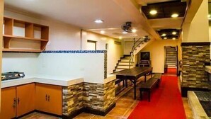 Amplia sala de estar con cocina, una mesa de comedor y una escalera que sube a otro nivel.