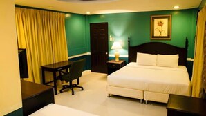 Habitación de hotel con cama, escritorio, silla y lámpara.