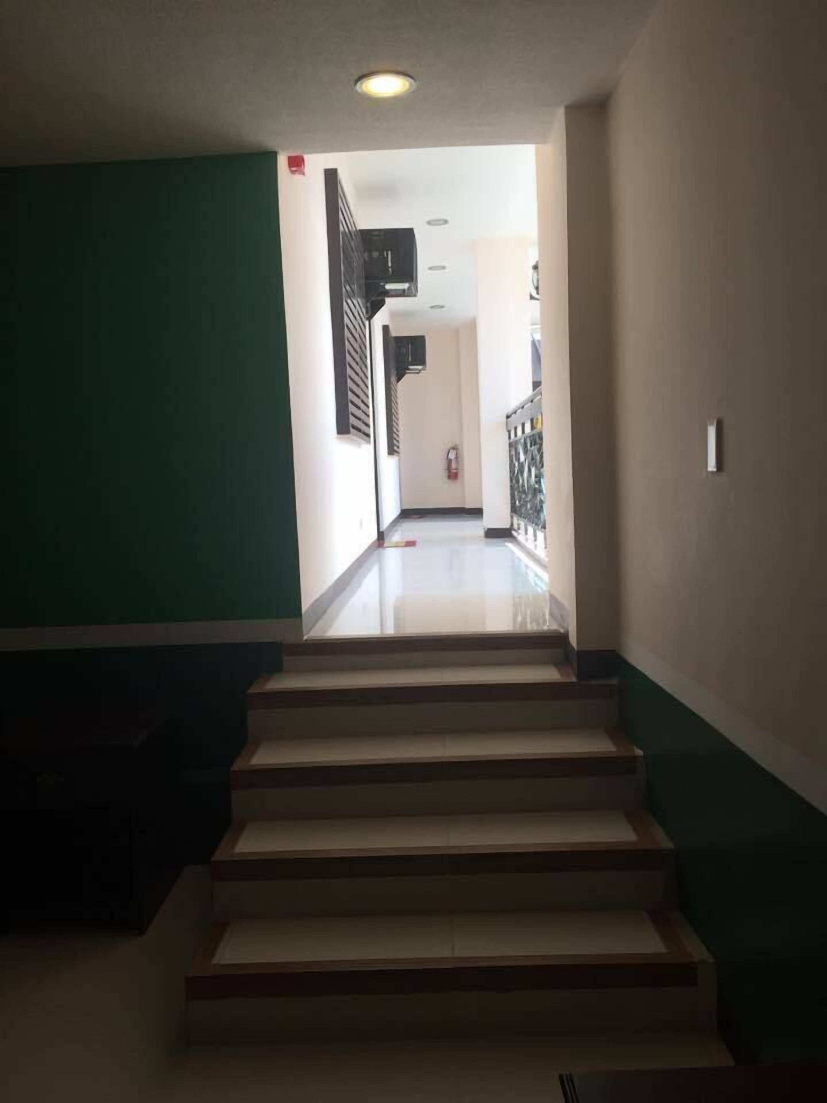 Una escalera que conduce a un rellano con un extintor en la pared.