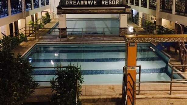 Un resort con piscina, un cartel que dice "Dreamwave Resort" y una escalera que lleva al área de la piscina.