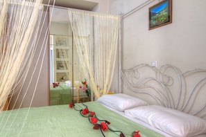 Una cama con sábanas blancas, una colcha verde y rosas rojas.