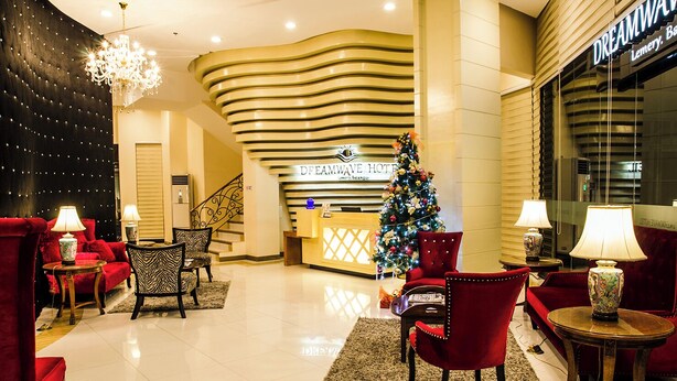 Un vestíbulo de hotel con mostrador de recepción, asientos rojos, un árbol de Navidad y una araña.