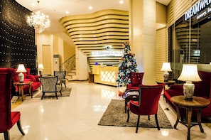 A hotel lobby with a reception desk, red seating, a Christmas tree, and a chandelier. - Dreamwave Hotel Lemery (Lemery)