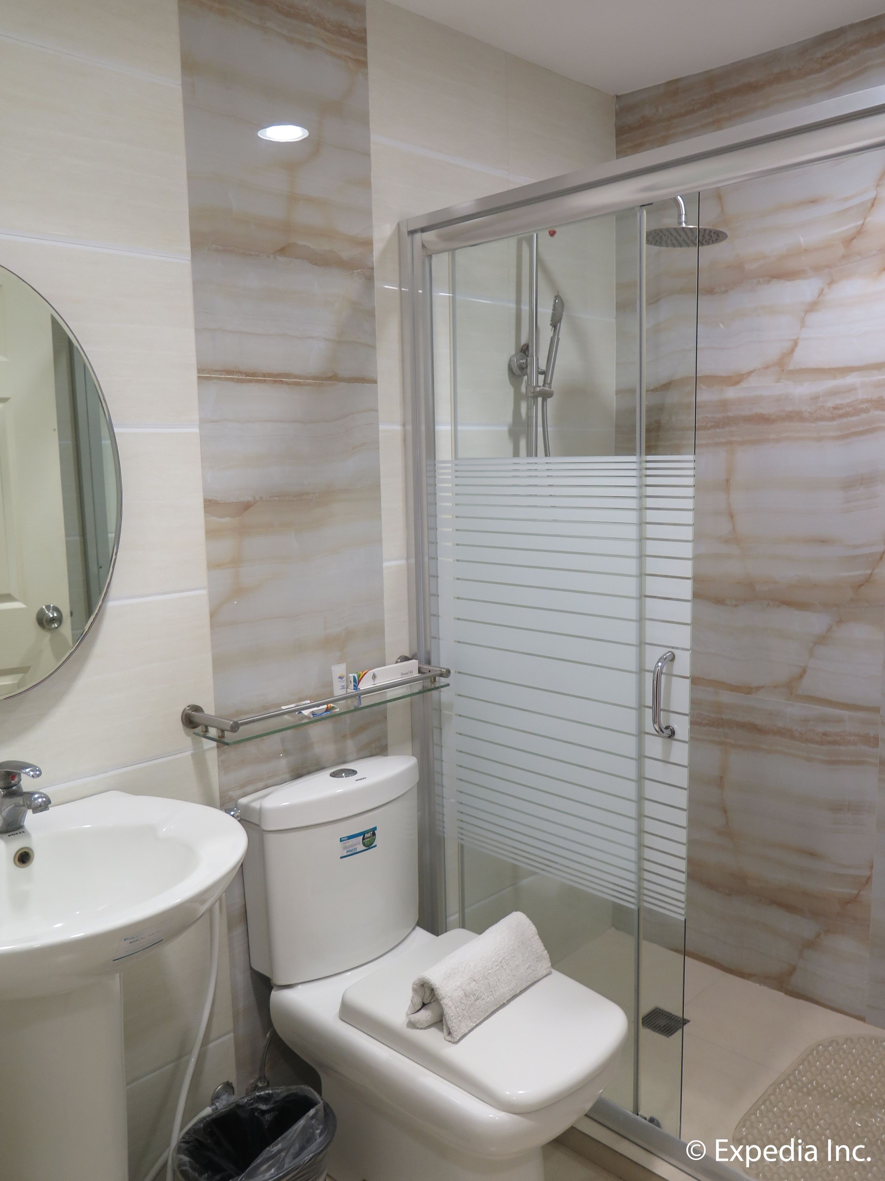 A bathroom with a glass-enclosed shower, a toilet, a sink, and a mirror.