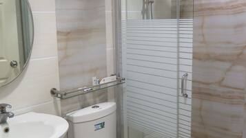 A bathroom with a glass-enclosed shower, a toilet, a sink, and a mirror.