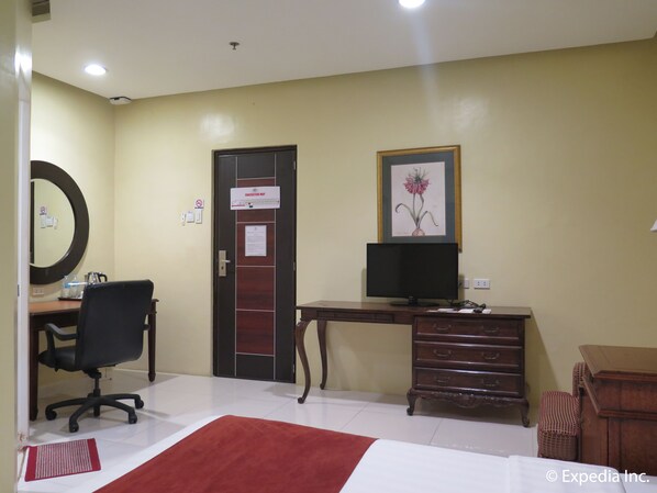 A hotel room with a desk, chair, computer, dresser, and a framed picture on the wall. - Dreamwave Hotel Lemery (Lemery)