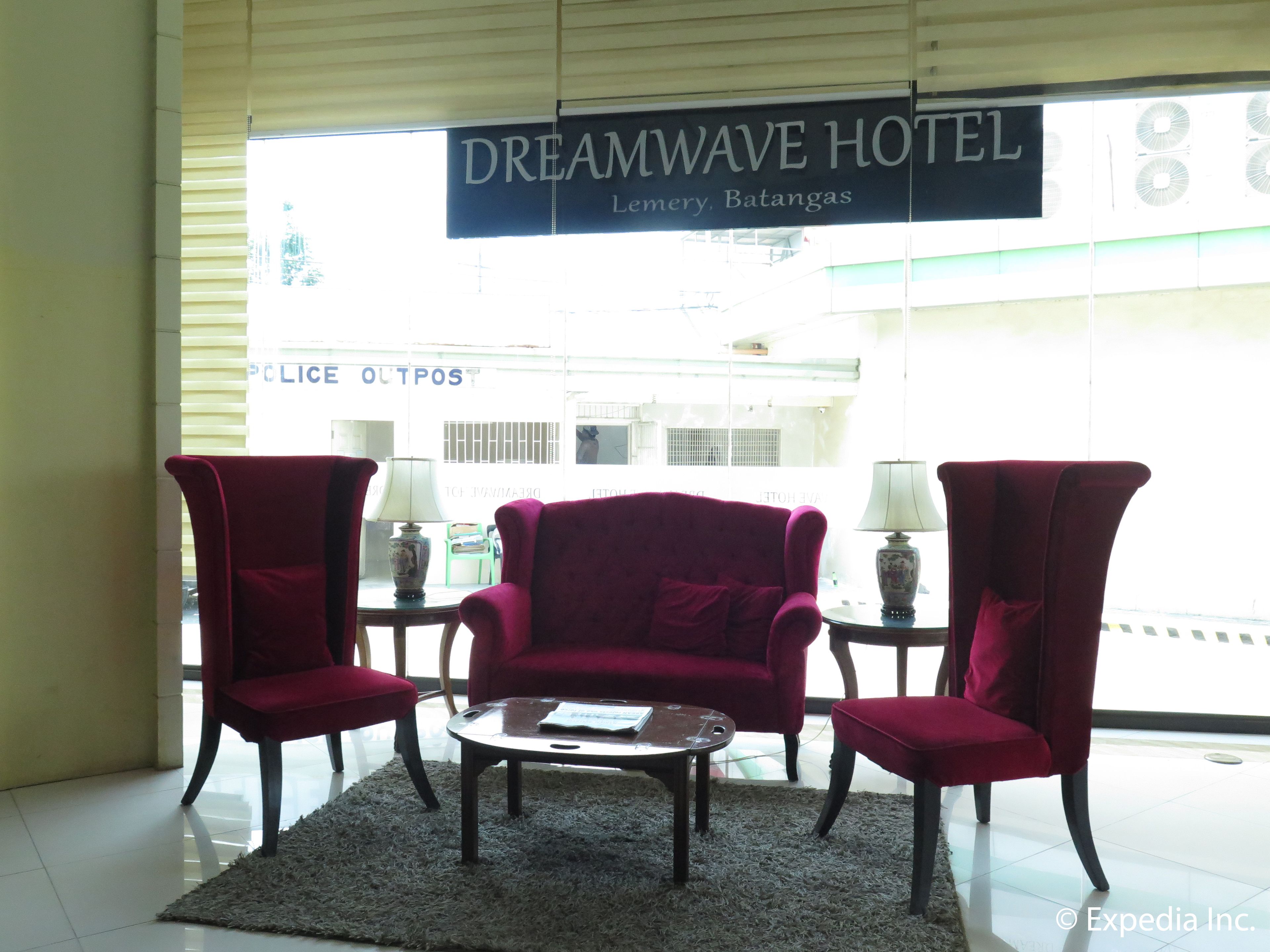 Un vestíbulo de hotel con un conjunto de sofá rojo, una mesa de centro y dos lámparas. Un letrero arriba indica "DREAMWAVE HOTEL".
