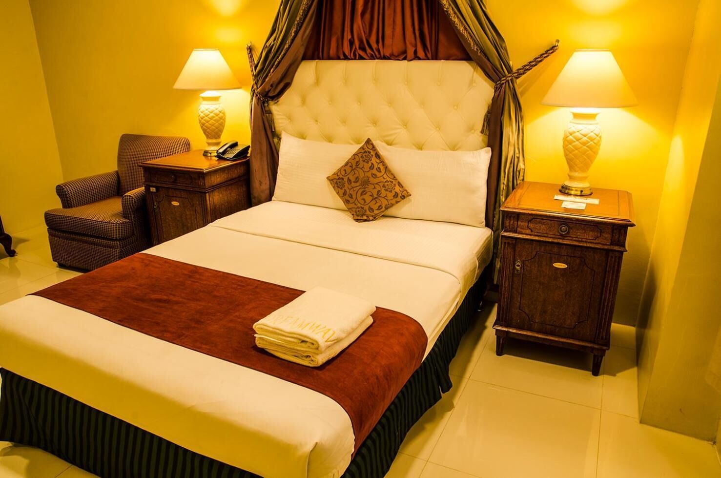 A well-appointed hotel room with a large bed, two bedside tables, a nightstand, and a chair.