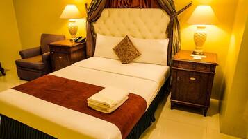 A well-appointed hotel room with a large bed, two bedside tables, a nightstand, and a chair.