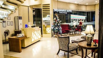 Un vestíbulo de hotel con una recepción, un árbol de Navidad y un sofá rojo.