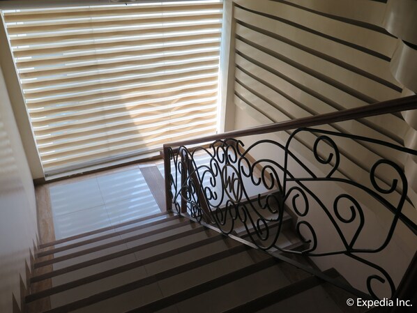 A staircase with a metal railing and striped floor tiles.