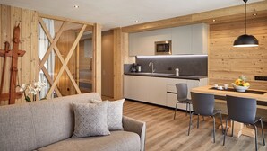 A modern kitchen with a wooden interior, a dining area with a table and chairs, and a sofa with cushions. - Residence Settsass (Corvara in Badia)